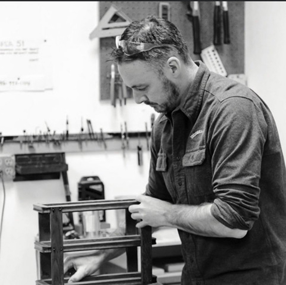 Man with beard working on a wood project. Picture is in black and white.